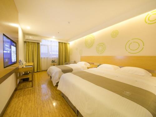 a hotel room with three beds and a flat screen tv at GreenTree Inn Beijing Tongzhou District Xuxinzhuang Subway Station Express Hotel in Beijing