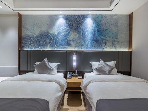 ein Hotelzimmer mit 2 Betten und einem Gemälde an der Wand in der Unterkunft GYA Xuzhou High Speed Railway Station West Exit Station Hotel in Xuzhou