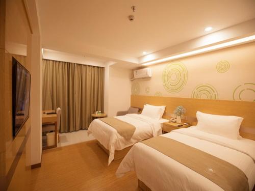 a hotel room with two beds and a flat screen tv at GreenTree Inn Haikou Chengmai Old Town Software Park Business Hotel in Bailian