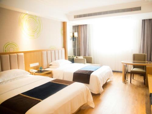 a hotel room with two beds and a table at GreenTree Inn JiangSu Taizhou Taixing Middle Guoqing Road Business Hotel in Taixing