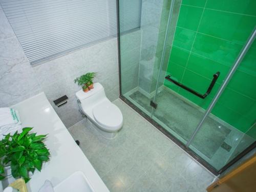a bathroom with a toilet and a glass shower at GreenTree Inn Yangzhou Jiangdu Xiaoji Town South Zhongxing Road Express Hotel in Xiaoji
