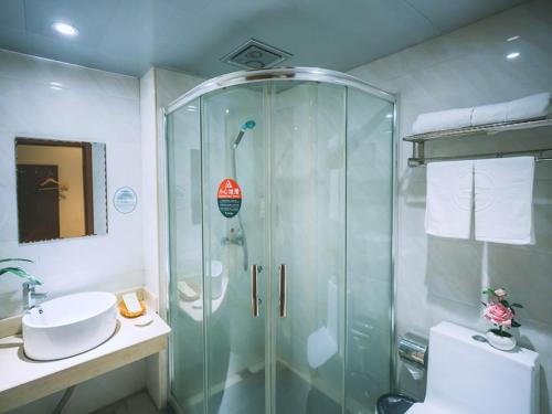a bathroom with a glass shower and a sink at GreenTree Inn Zhejiang Lishui Suichang Longgu Road Express Hotel in Suichang
