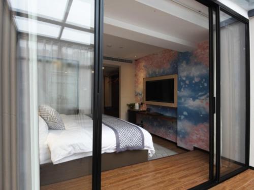 a bedroom with a bed and a sliding glass door at GME Hefei Sanxiaokou Chenghuang Temple Xinghua Park Hotel in Hefei