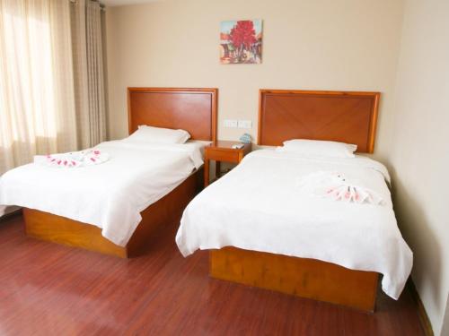a bedroom with two beds with white sheets at GreenTree Inn Rizhao West Station Suning Plaza in Rizhao