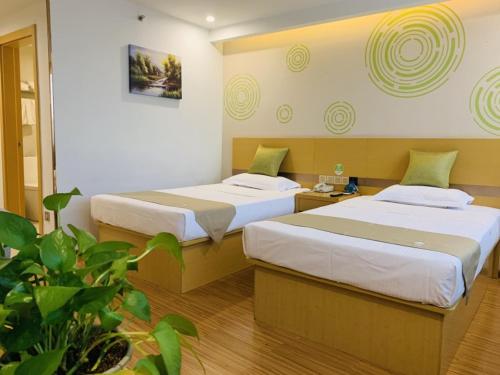 a hotel room with two beds and a plant at GreenTree Inn Tianjin Hedong District Tianjin Station Front Square Express Hotel in Tianjin