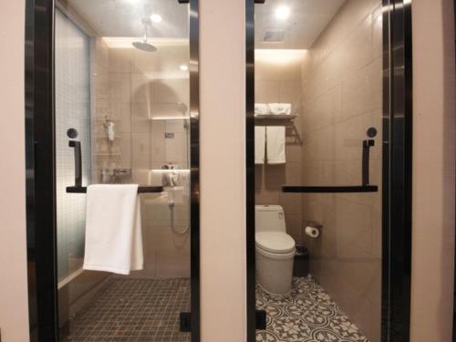 a bathroom with a toilet and a shower with towels at GME Hefei Sanxiaokou Chenghuang Temple Xinghua Park Hotel in Hefei