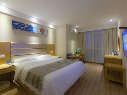ein Hotelzimmer mit einem großen Bett und einem Flachbild-TV in der Unterkunft GreenTree Inn JiangSu XuZhou JiaWang Government Express Hotel in Xuzhou