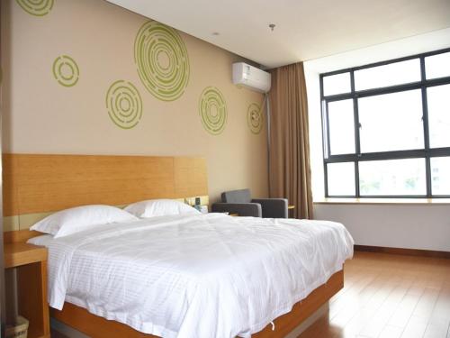 Un dormitorio con una gran cama blanca y una ventana. en GreenTree Inn Wuxi Huishan District Yangshan Town Jiayang Life Plaza Business Hotel, en Wuxi