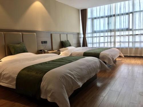 two beds in a hotel room with a large window at GreenTree Inn Jiangsu Yangzhou Gaoyou Tonghu Road Beihai Express Hotel in Gaoyou