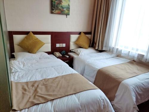 a hotel room with two beds and a window at GreenTree Inn ShangHai South JiangYang Road South ChangJiang Road Express Hotel in Baoshan