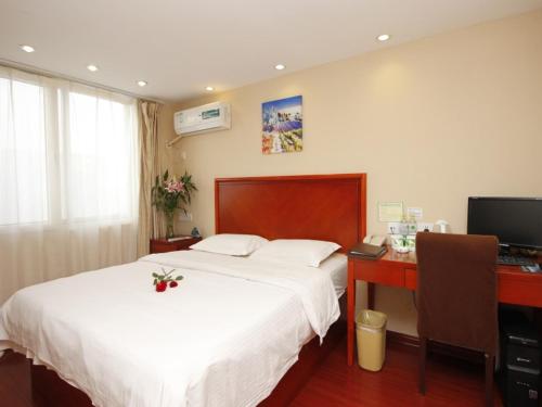 a bedroom with a bed and a desk and a computer at GreenTree Inn Rizhao West Station Suning Plaza in Rizhao