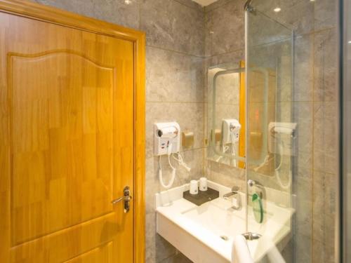 a bathroom with a sink and a glass shower at GreenTree Inn Xingtai City Neiqiu County 107 National Road Business Hotel in Xingtai