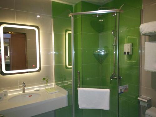 a green bathroom with a shower and a sink at GreenTree Inn Jinzhong Yuci District North Huitong Road Express Hotel in Jinzhong