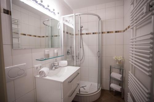 a white bathroom with a shower and a sink at Alpenglück Whg. 20 in Garmisch-Partenkirchen