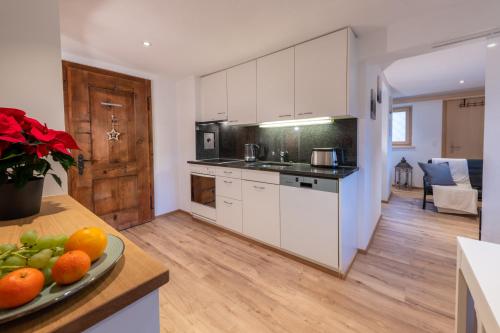 a kitchen with white cabinets and a plate of fruit on a counter at Florin Ferien in Klosters