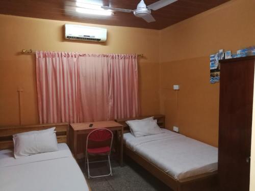 um quarto com duas camas e uma cadeira vermelha em Feehi's Place em Acra