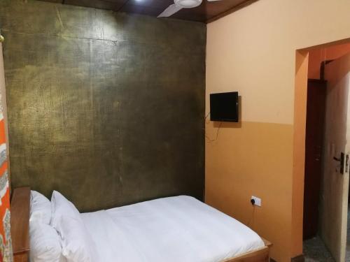 uma pequena cama num quarto com uma parede em Feehi's Place em Acra