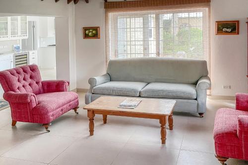 a living room with a couch and two chairs and a coffee table at Coral Sea private beachfront panorama with infinity pool in Tuckerʼs Town