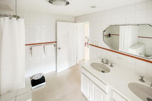 a white bathroom with a sink and a mirror at Coral Sea private beachfront panorama with infinity pool in Tuckerʼs Town