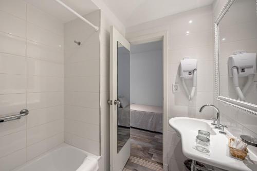 a white bathroom with a sink and a shower at Sennac Hotel in Mar del Plata