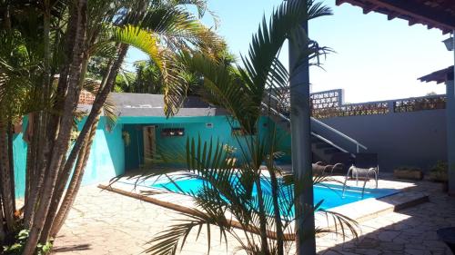 een blauw huis met een zwembad en palmbomen bij Hotel Pousada Jaguariuna in Jaguariúna