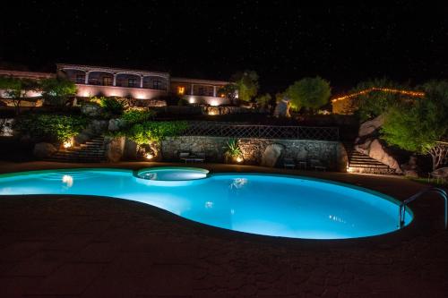 a swimming pool in a yard at night with lights at Moma Hotel Cannigione in Cannigione