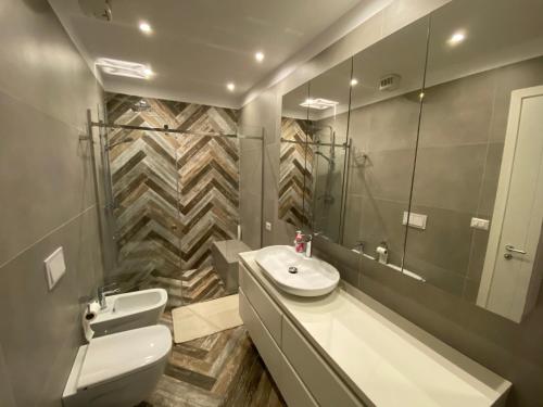 een badkamer met een wastafel, een toilet en een spiegel bij Mel’s Place in Tirana