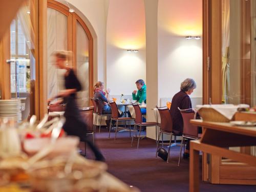a group of people sitting at tables in a restaurant at Hotel VICTORIA Nürnberg in Nürnberg