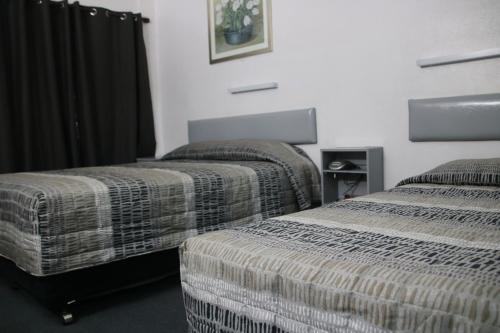 2 Betten in einem Hotelzimmer mit Röcken in der Unterkunft Bourbong St Motel in Bundaberg