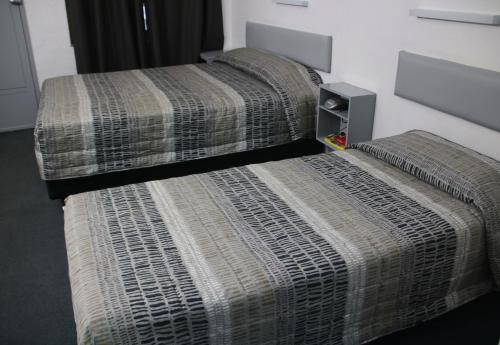 two beds sitting next to each other in a room at Bourbong St Motel in Bundaberg