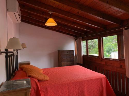 ein Schlafzimmer mit einem roten Bett mit einer roten Decke in der Unterkunft Cabañas Bosques del Centro in Mina Clavero