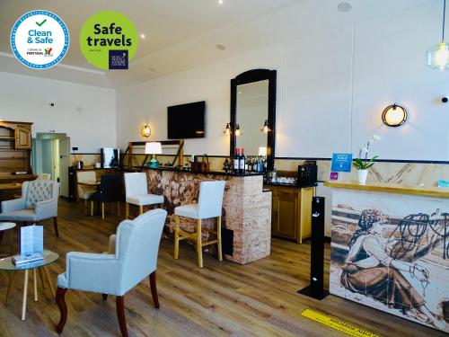 a salon with a bar with chairs and a mirror at Poveira Hotel in Porto