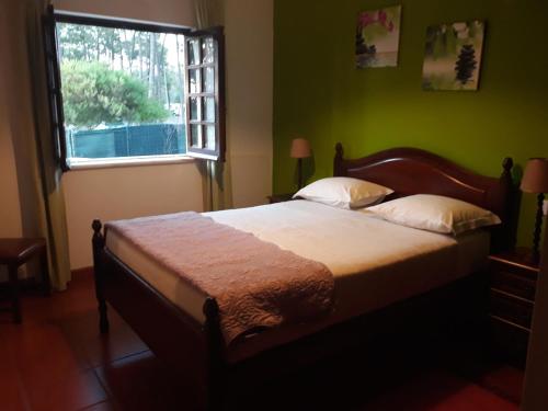 a bedroom with a large bed with a window at Ana Mónica Pereira in Vila Nova de Milfontes