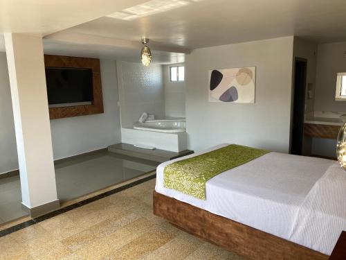 Hotel Aqua Rio في تيخوانا: غرفة نوم بسرير وحمام مع حوض استحمام
