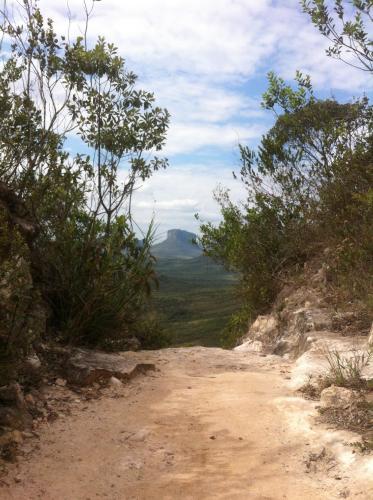 uma estrada de terra com árvores ao lado de uma montanha em Pousada Pico Da Vila em Vale do Capão