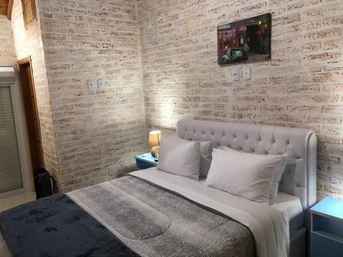 a bedroom with a bed and a brick wall at Chalé Centro de Monte Verde in Monte Verde