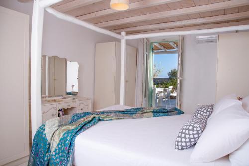a bedroom with a white bed with a window at Villa Mando in Super Paradise Beach