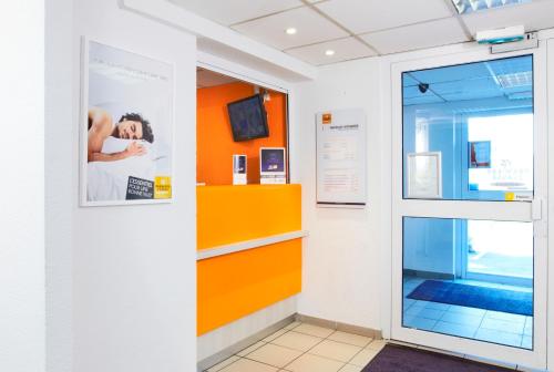 a hallway with an orange wall and a glass door at Premiere Classe Montreuil in Montreuil