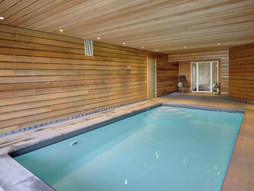 ストゥモンにあるComfortable chalet with indoor pool hammam and sauna near Stoumontの壁に囲まれた木製の部屋の中にある大きなスイミングプール