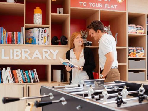 a man and a woman reading a book in a library at Aparthotel Adagio Access Dijon République in Dijon