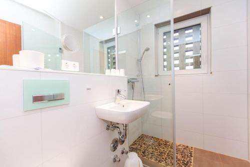 a white bathroom with a sink and a shower at Wohnung-re-Sylter-Boje in Wenningstedt