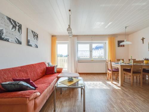a living room with a red couch and a table at Spacious apartment in the Bavarian Forest in Viechtach