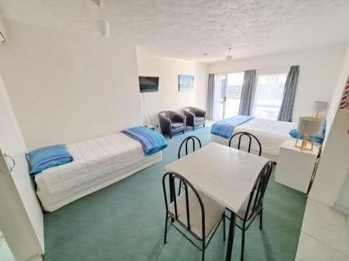 una habitación con dos camas y una mesa y sillas en Paihia Star Motel, en Paihia