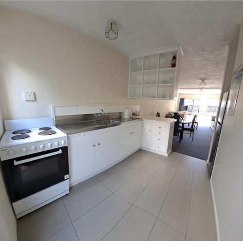 Una cocina blanca con estufa y fregadero. en Paihia Star Motel, en Paihia