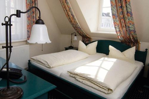 a bed in a room with a lamp and a window at Hotel Reuterhaus Wismar in Wismar