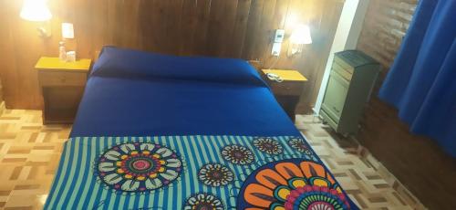 a bed with a blue bedspread with flowers on it at Apartamento Agustín in San Bernardo