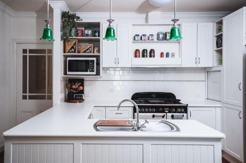 a kitchen with white cabinets and a sink and green lights at Johnstone Terrace in Castlemaine