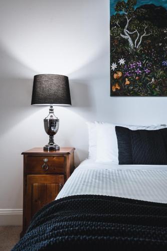 a bedroom with a bed and a lamp on a night stand at Johnstone Terrace in Castlemaine