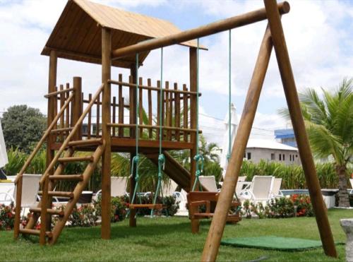 um parque infantil de madeira com um baloiço num quintal em Laguna Beach Flat em Porto de Galinhas