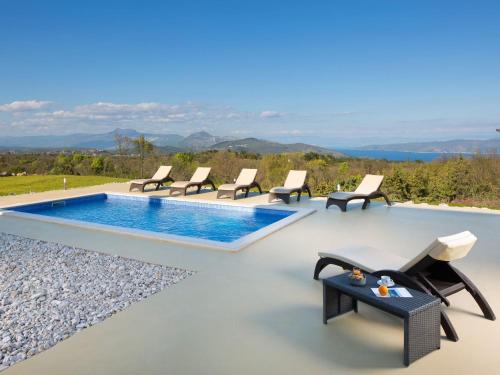 a pool with chairs and a table on a patio at Detached villa with private pool located on hill overlooking Kvarner in Hrvatini
